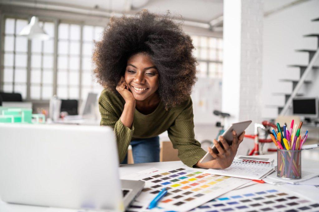 gig economy worker leaning over desk with colour swatches and laptop