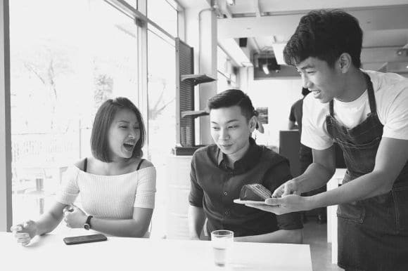 Teenage clerk taking customers' orders at a tea and coffee shop.