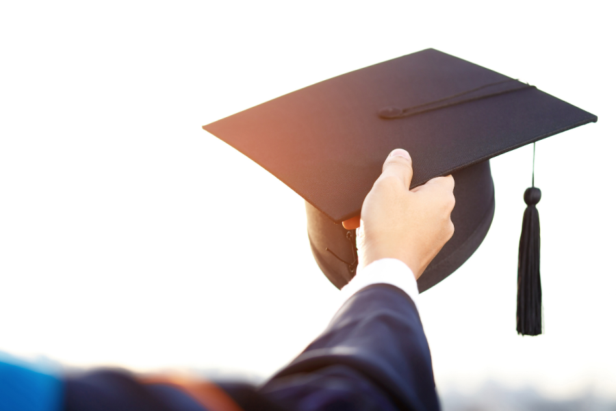 up close shot of a graduation cap being held by a graduate.